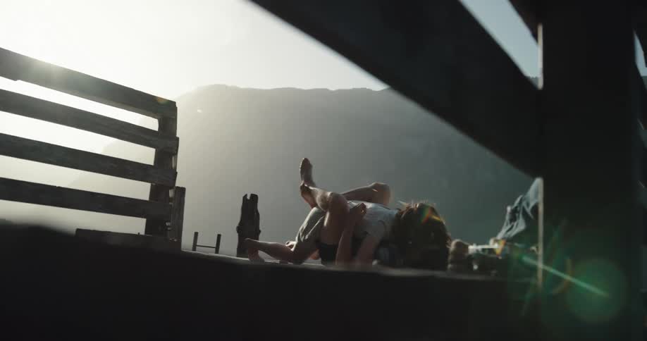 A couple lay down and kiss on the pier