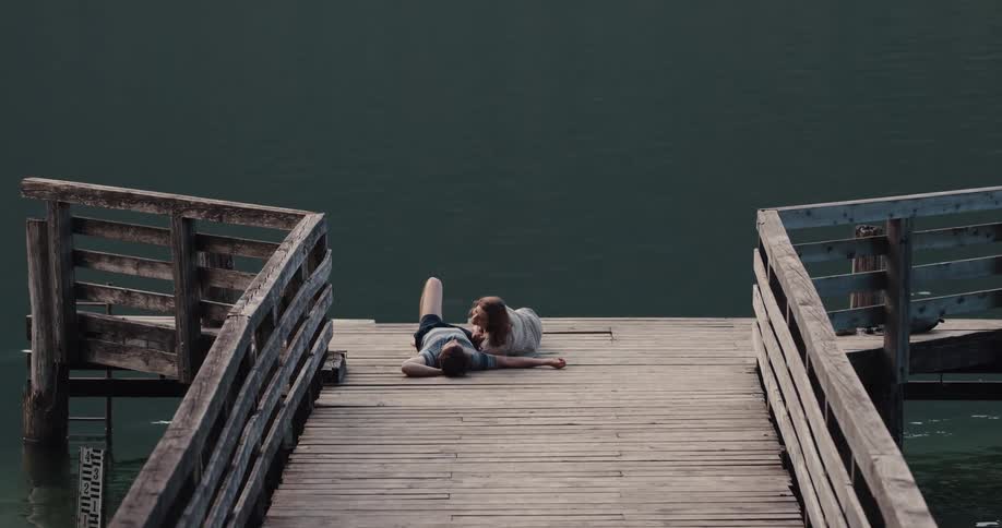 Two people that are hugging laying on a pier