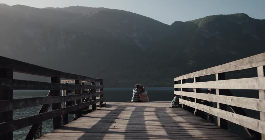 Two people cuddle together at the end of a pier on the lake