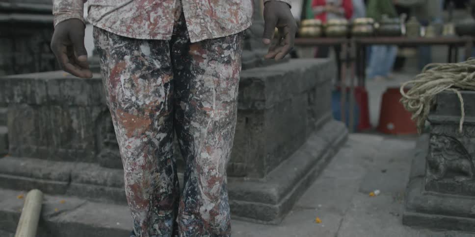 Panning up a man wearing clothes covered with paint