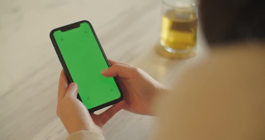A woman is holding a cellphone and sitting at a table