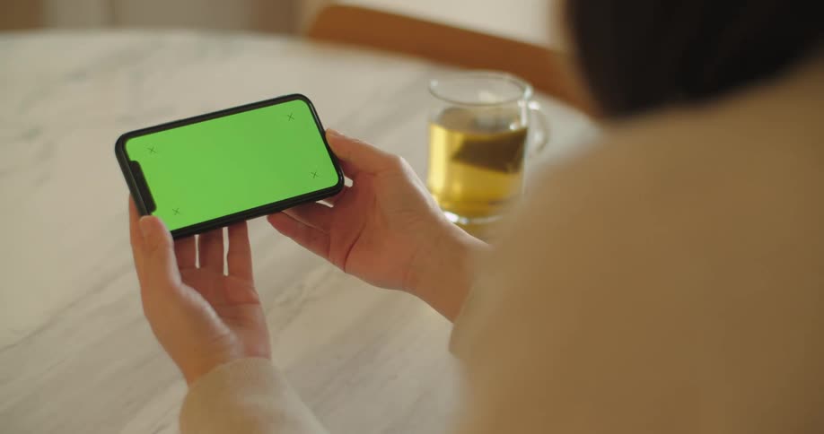 A woman is sitting at a table and looking at a cell phone