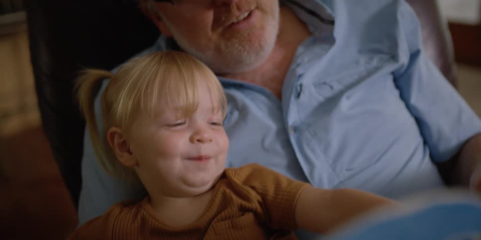 A grandfather and granddaughter reading books together