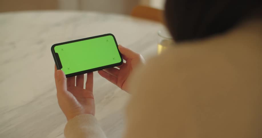 A woman is sitting at a table and looking at a cell phone