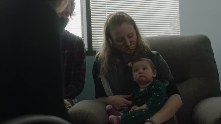Parents sit with their infant daughter in a doctors office