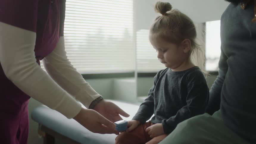 A nurse tends to a toddler girl in a doctors office