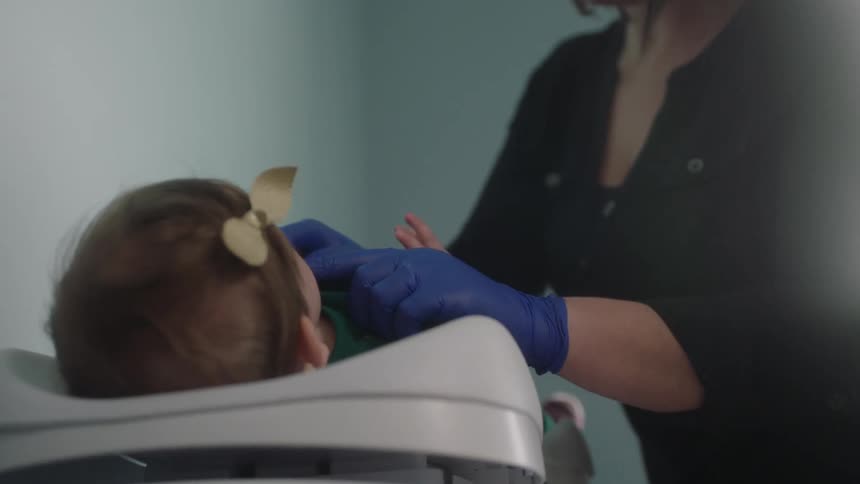 A woman feels around in a babies mouth
