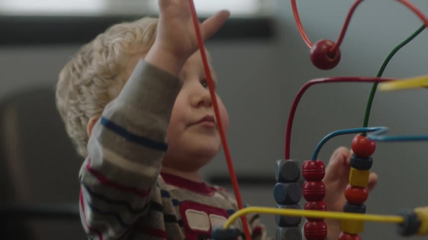A young boy plays with a toy in a waiting room during the day