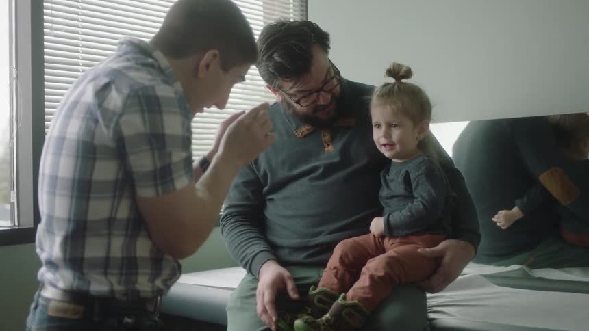 A doctor talking to a child and her father in a doctors office