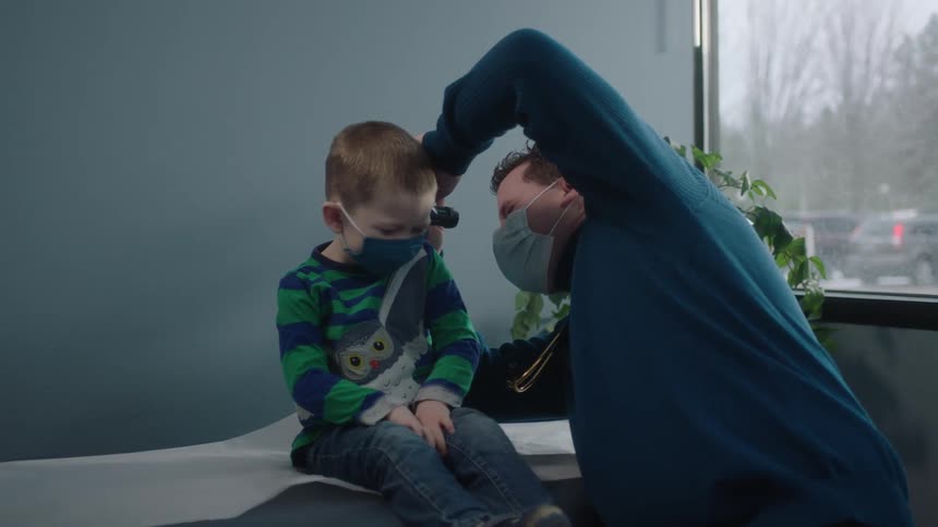 Doctor examines the ear of a little boy with a medical instrument