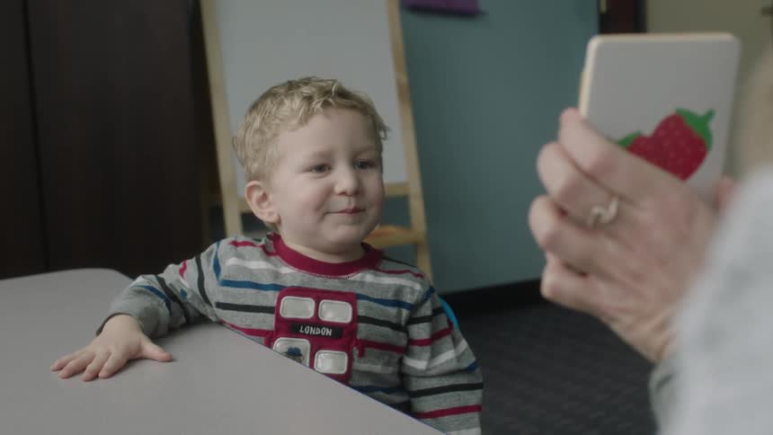 A person is showing a child flash cards in class