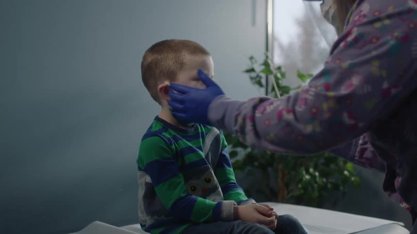 A boy in a clinic with a nurse with gloves putting a cotton swab in his nose