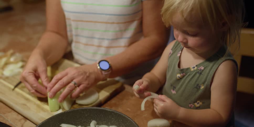 A child helps an elderly woman place vegetables on a plate