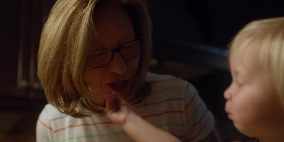 A grandmother smiles after her granddaughter feeds her some shredded cheese
