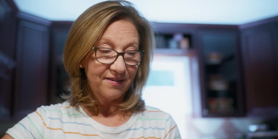 Woman wearing eyeglasses talks while standing in kitchen
