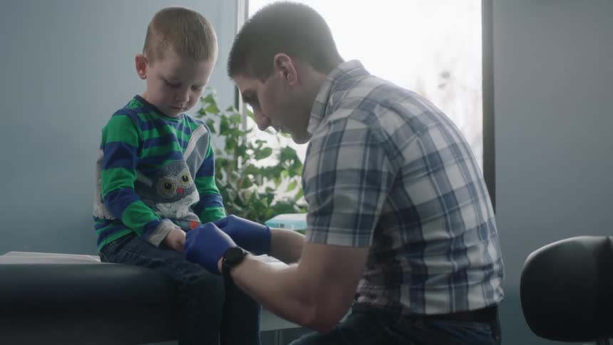 A doctor puts stitches in a little boys hand