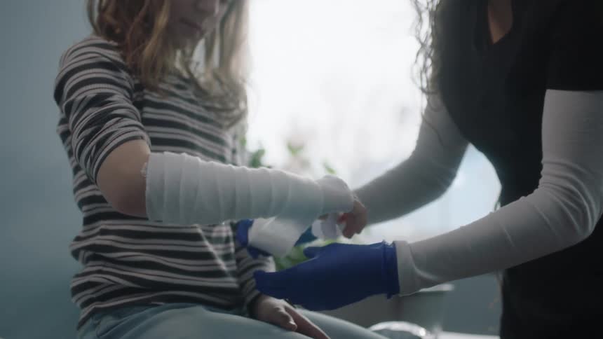 A nurse wraps a young girls arm in a clinic
