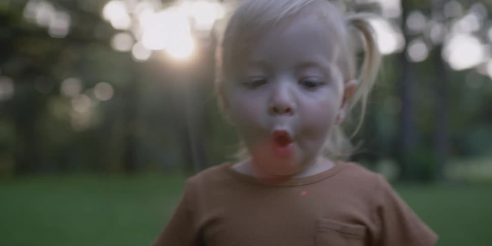 Blonde little girl walks in the forest at sunset