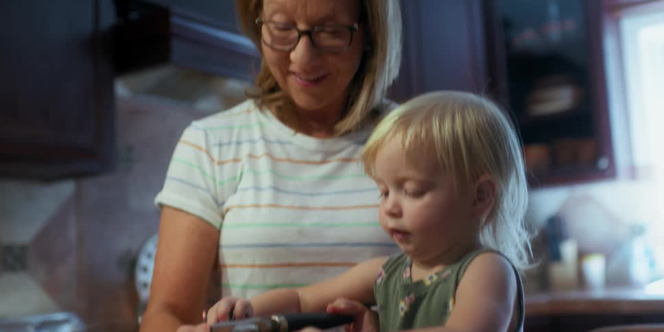 A woman helps her grand daughter open a can as they cook together
