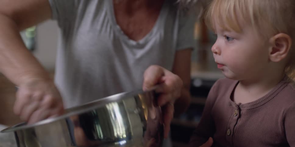 A grandma smiles at her granddaughter as she mixes batter in a bowl