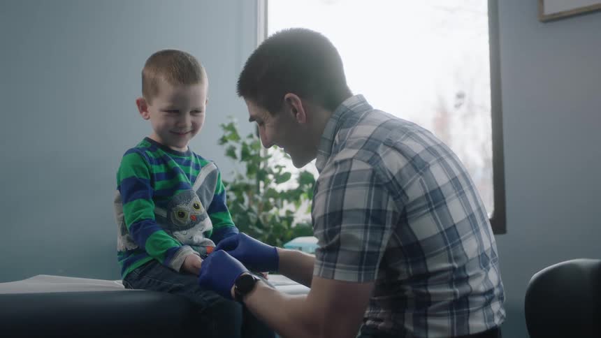 Doctor with shortsleeved shirt injects boy in the clinic