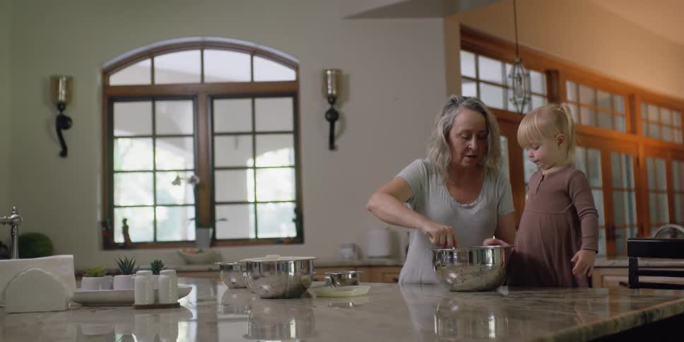 A mother and daughter mixing things in a bowl in a kitchen
