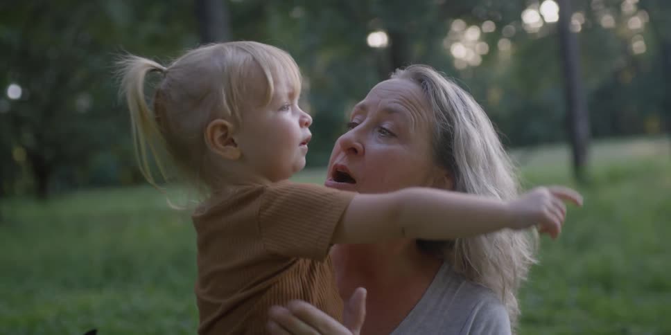 A woman hugs a young girl in a field during the day