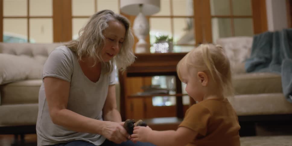A woman and a girl in a room sitting on the floor playing with toys