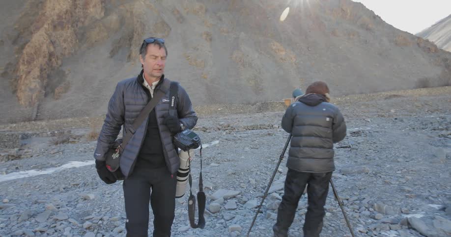 People carrying cameras walk and set up on a mountain