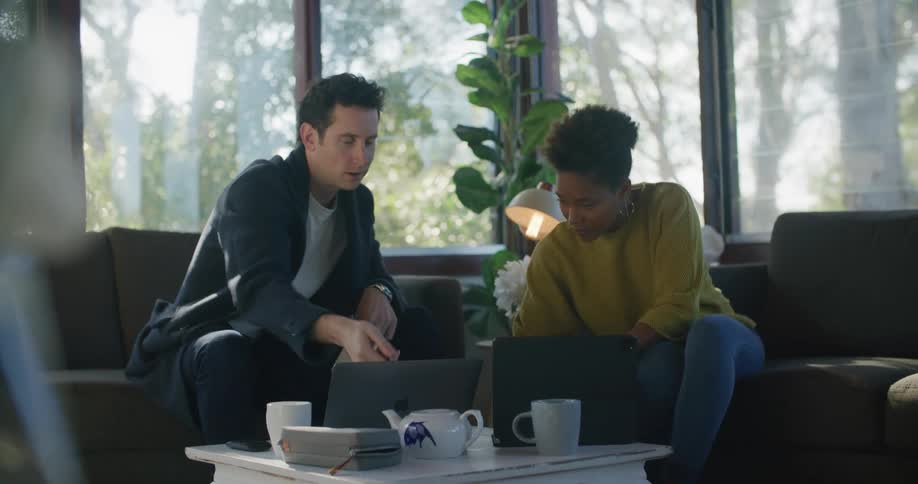 A man and woman look at a laptop and talk