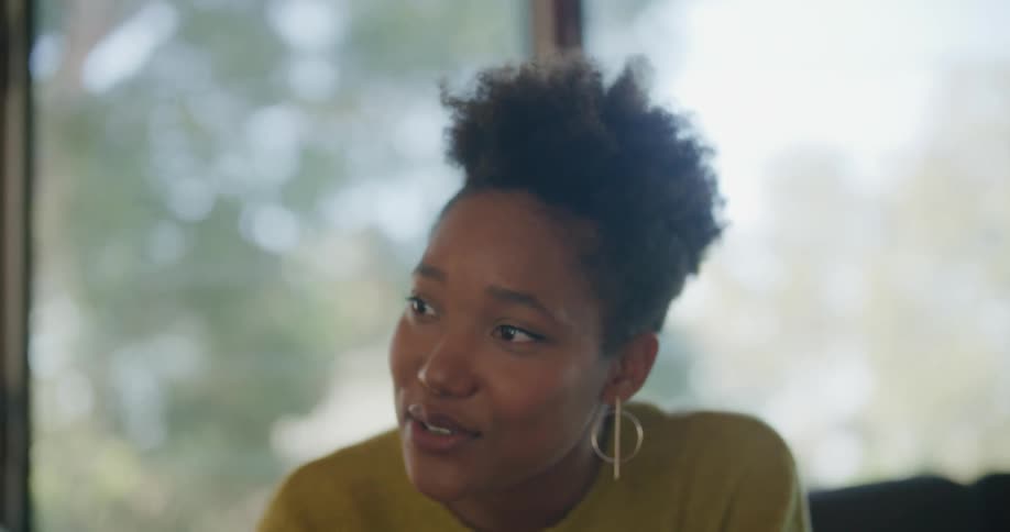 Black woman smiles and talks to a person sitting next to her
