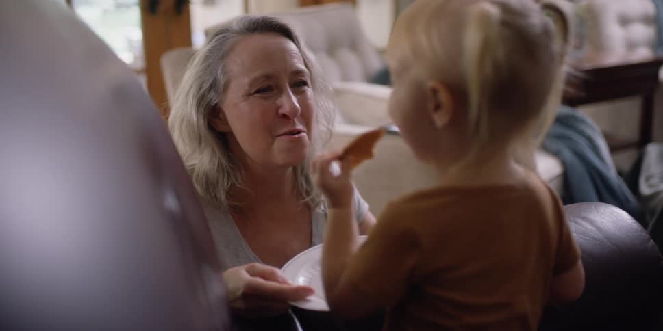 A child feeds a cookie to a woman