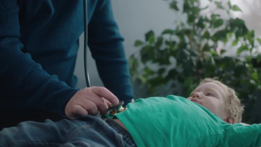 A doctor is examining a child in his office