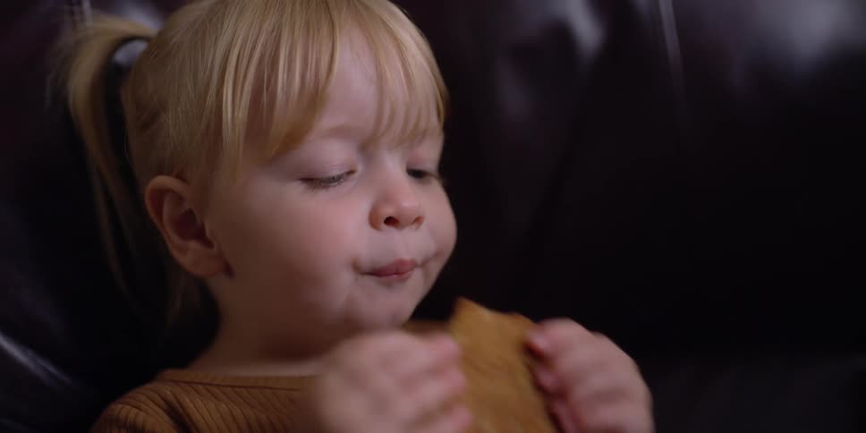 A girl in a room sitting on a couch eating a cookie on a plate
