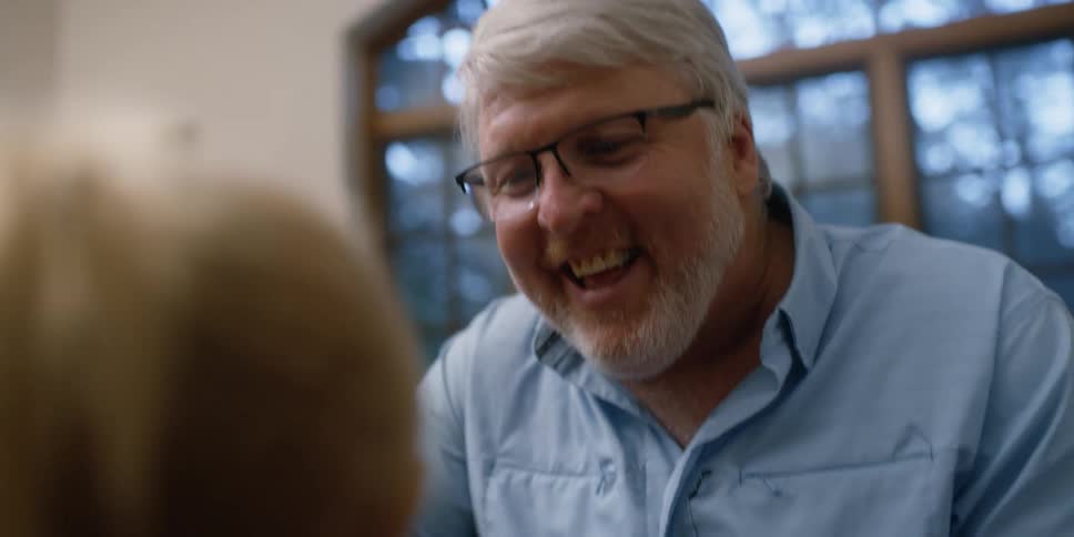 A man makes funny faces at a young girl indoors during the day