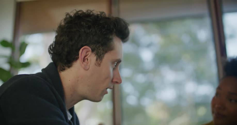 Woman and man consult over laptop sitting near window