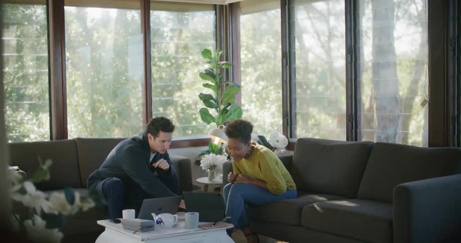 A man and woman are talking and looking at a laptop together