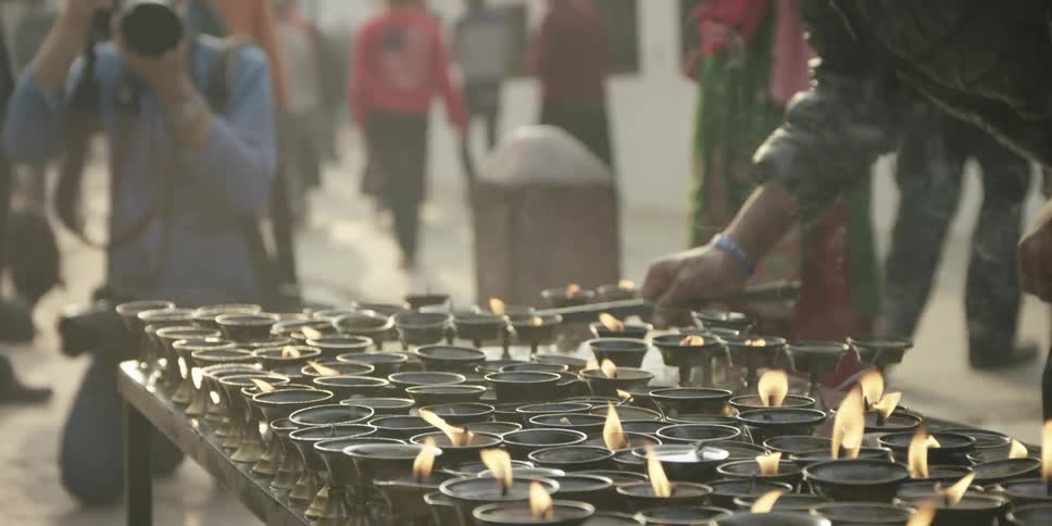 Many candles burning outside as a man takes a picture