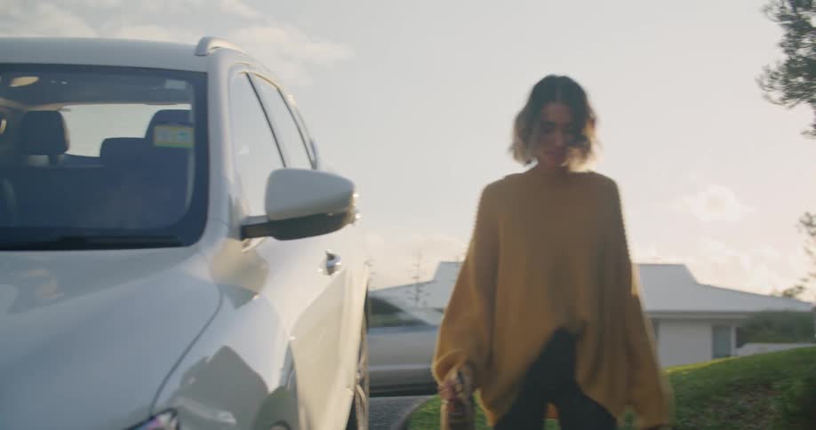 A man and a woman stepping out of the vehicle with trees the sky and clouds in the background