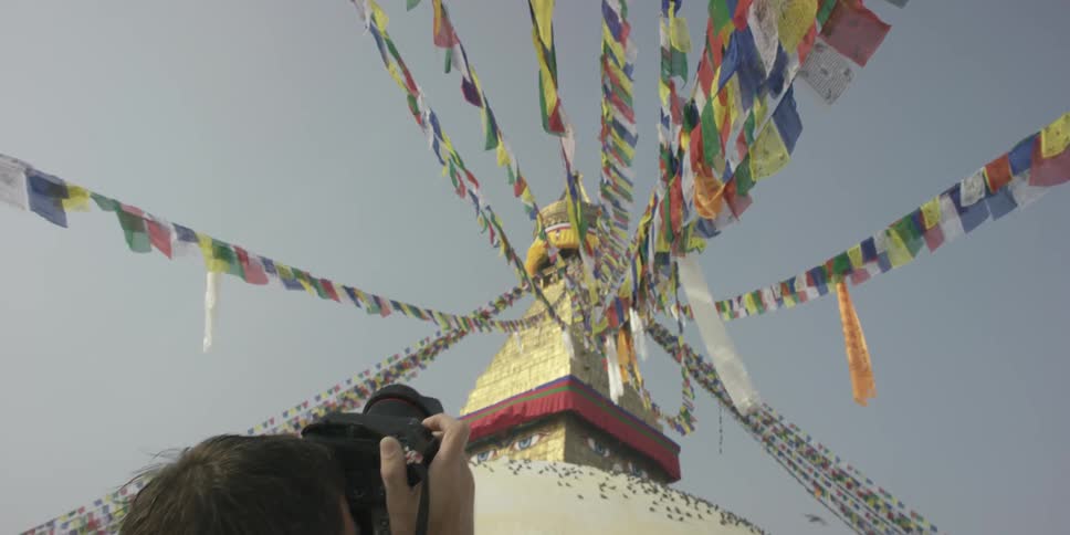 A man takes pictures of flags fluttering on a building