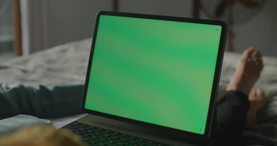 Two people lie on bed with laptop