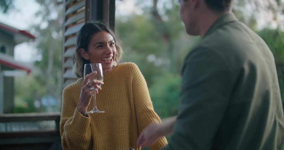 Man and woman stand in open air structure drinking and talking