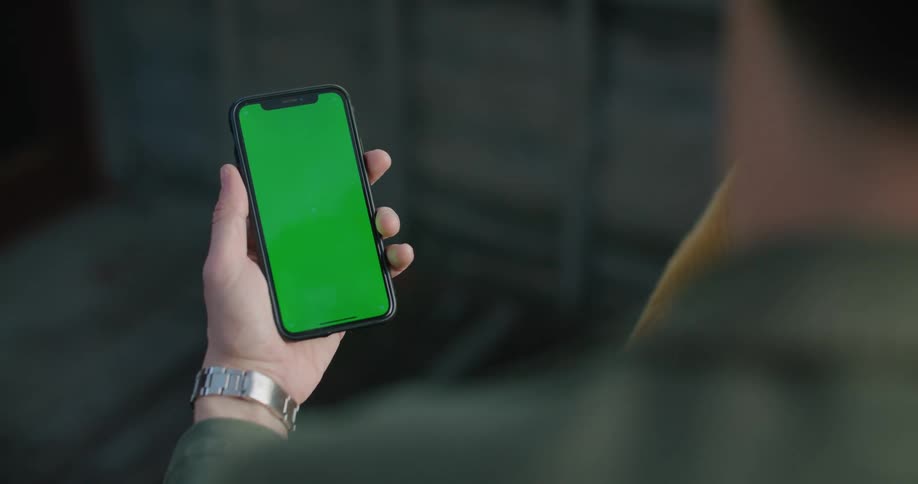 A man in a room looking at a smart phone