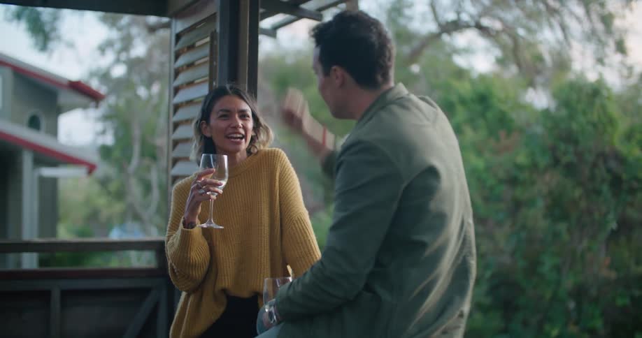 Man and woman hold wine glasses while they are outside talking and laughing