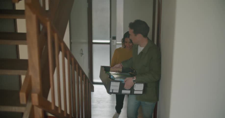 Husband and wife are walking up a flight of stairs in their house