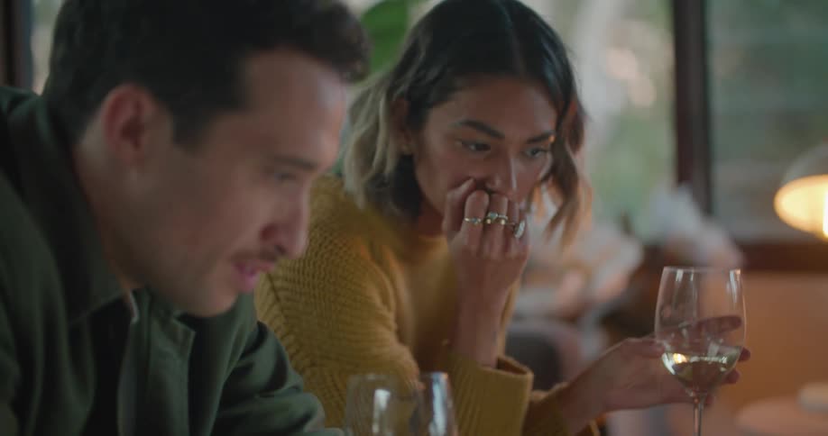 Man and woman hold wine glasses while they look at a laptop screen