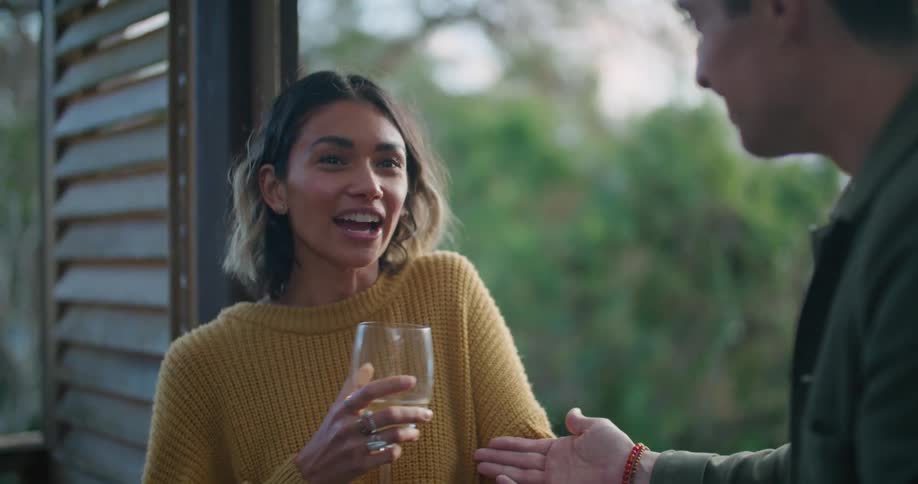 A man and woman standing outdoors drinking wine