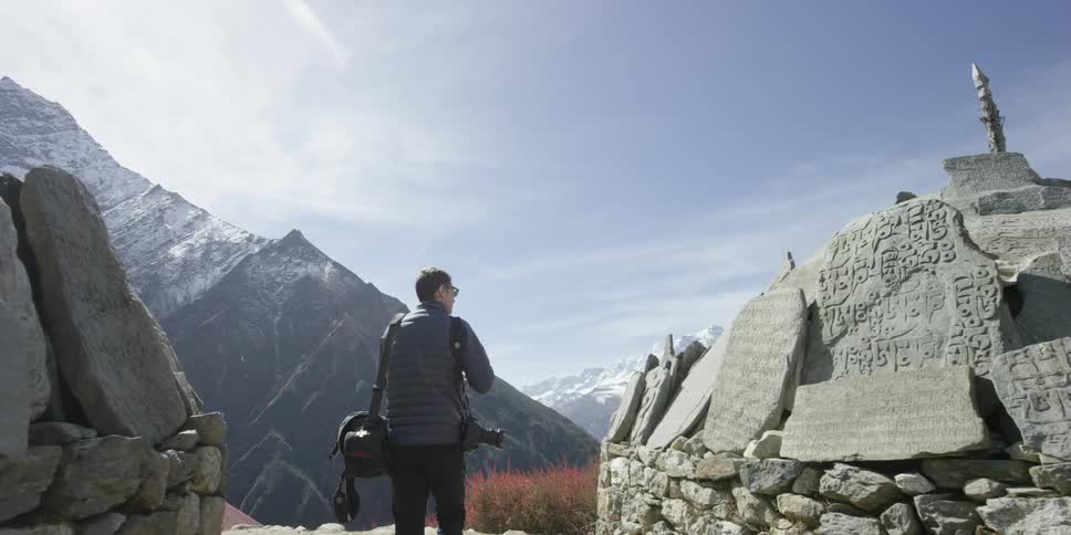 A man walks uphill holding a bag on a sunny day
