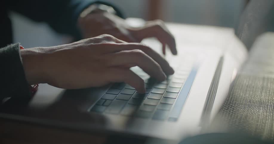 A man types on his laptop while sitting at his kitchen table
