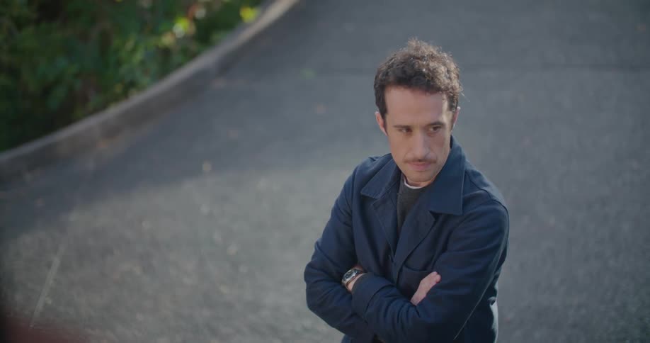 Man turns his head as he stands outdoors with his arms crossed